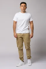 Pantalón cargo color beige de gabardina, con corte ajustado, bolsillos laterales con fuelle y puños elásticos en los tobillos.