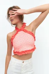 Top de escote halter confeccionado en broderie de algodón y bordado con hilo color coral. Enmarcado con voladitos de lino a tono.