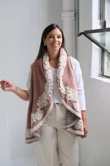 Chaleco abierto de textura suave, color rosa con diseño floral en relieve de color crema en los bordes y el interior. Presenta un corte holgado y fluido.