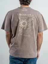 Remera de corte oversize color marrón con efecto lavado, cuello redondo y estampa frontal con la frase 'URUGUAY noma!'.