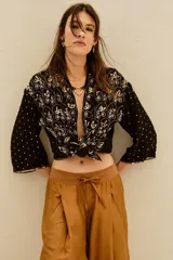 Kimono de corte holgado en color negro, con mangas tres cuartos y diseño bordado con motivos florales y detalles en hilo dorado. Presenta un cierre frontal anudado y forro interior.