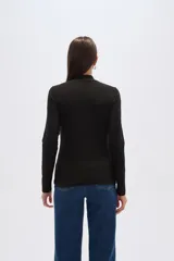 Remera de manga larga con cuello alto, confeccionada en tejido de viscosa y elastano con estampado a cuadros en tonos azul, gris y negro.