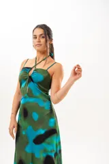 Vestido largo con estampado abstracto en tonos verdes, azules y negros. Presenta tirantes finos y cuello halter cruzado con detalle de abertura en el pecho.