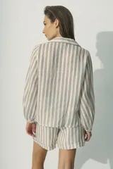 Camisa de manga larga con cuello camisero y cierre frontal con botones. Diseño a rayas verticales color beige y blanco, con dos bolsillos de parche en el pecho.