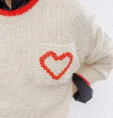 Buzo de punto color crema con detalles en rojo en el cuello, puños y ruedo. Presenta un bolsillo frontal en el pecho con un corazón bordado en relieve.