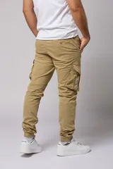 Pantalón cargo color beige de gabardina, con corte ajustado, bolsillos laterales con fuelle y puños elásticos en los tobillos.