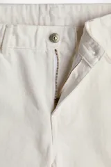 Bermuda de cinco bolsillos en denim de algodón rígido, corte baggy con cierre de botón y bajo deshilachado.