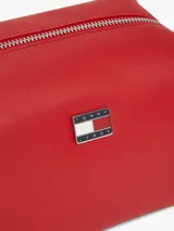 Bandolera Tommy Jeans de color rojo, diseño estructurado de silueta cuadrada con acabado liso. Cuenta con cierre de cremallera, correa ajustable y un colgante lateral de cordón trenzado con adorno en forma de corazón. Incluye la insignia con el logo de la marca en la parte delantera.