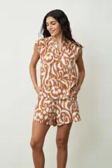 Blusa negra sin mangas, con cuello mao y abertura frontal con botones. Presenta frunces en la zona de los hombros, dándole un calce holgado.