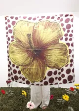 Pañuelo cuadrado de gran tamaño con estampado central de una flor de hibisco en tonos amarillos y marrones, sobre un fondo blanco con lunares marrones.