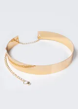 Cinto dorado de metal rígido, con cadena colgante y cierre ajustable.