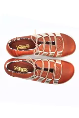 Zapato deportivo casual de cuero, con diseño de tiras laterales en contraste color marrón sobre base color crema. Presenta cierre con cordones y suela de goma con relieve.