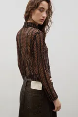 Camisa de encaje con diseño floral, de corte recto y manga larga, con cierre frontal de botones clásicos y cuello camisero.