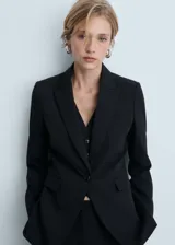 Blazer negro de corte entallado con solapas de muesca, hombros estructurados y cierre frontal de un botón. Cuenta con dos bolsillos de ribete delanteros, manga larga y abertura posterior.
