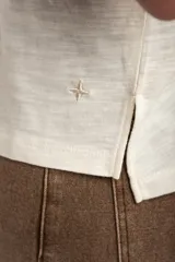 Remera de algodón flame color blanco marfil, con cuello redondo amplio y mangas cortas holgadas.