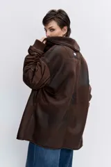 Cazadora de estilo bomber con diseño híbrido, combinando paneles de tela técnica en las mangas con un cuerpo de efecto piel desgastada y forro interior de corderito sintético. Presenta cierre frontal, cuello amplio y puños elásticos.