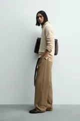 Jersey de punto color beige claro, con textura irregular y cuello redondo. Presenta un calce relajado y manga larga con puños y ruedo en rib.