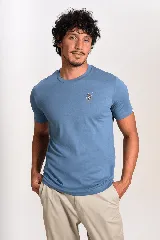 Remera de cuello redondo y manga corta en color azul, con un pequeño bordado de un pingüino esquiando en el pecho.
