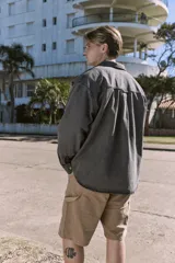 Camisa de denim negra de manga larga con cuello clásico y cierre con botones. Diseño amplio con bolsillos en el pecho.