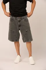 Bermuda gris oscuro de denim, corte ancho, con bolsillos laterales y traseros, y detalle de parches en las rodillas.