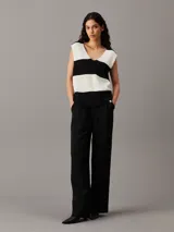 Chaleco de punto grueso con textura de canalé, diseño sin mangas y escote en V pronunciado. Presenta un patrón de rayas horizontales anchas en blanco y negro.