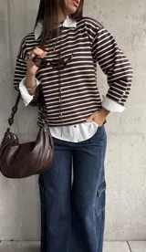 Sweater de punto a rayas horizontales en color chocolate y blanco, con cuello redondo y mangas largas con detalle de botones en los puños.