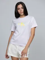 Remera de Calvin Klein color rosado claro, con cuello redondo, mangas cortas y corte regular. Presenta el monograma y el logo de la marca estampado en el pecho en tonos amarillo y verde.