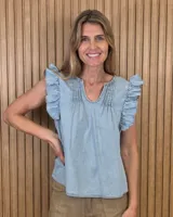 Musculosa de denim claro, sin mangas, con volados en los hombros, cuello redondo con abertura en V y alforzas decorativas en el frente.