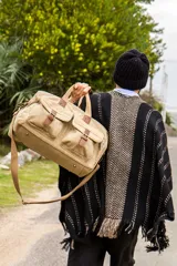 Ruana tejida de corte amplio y diseño abierto, con patrón de rayas verticales en tonos negro y beige, terminada con flecos en el ruedo.