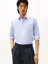 Camisa de vestir de manga larga, color celeste con rayas verticales blancas, cuello clásico y pequeño logo bordado en el pecho.