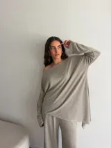 Conjunto gris melange compuesto por un buzo de cuello bote amplio y corte asimétrico con bolsillos, y un pantalón largo de corte recto y holgado.