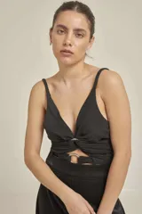 Top negro con breteles finos y escote en V. Presenta un nudo con aro metálico en la parte inferior del busto y un corte en el abdomen.