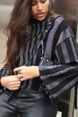 Sweater tejido de punto a rayas horizontales negras y plateadas, con cuello alto, mangas tres cuartos y calce oversize.