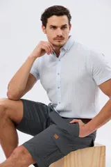 Bermuda cargo de gabardina en color gris oscuro, corte recto, con bolsillos laterales con solapa y cierre de botones y cremallera.