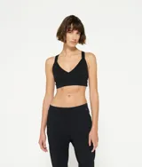 Top deportivo negro con escote en V y tirantes anchos cruzados en la espalda. Confeccionado en mezcla de algodón orgánico, ofrece gran elasticidad y sujeción.