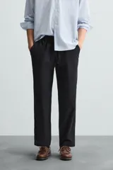 Pantalón de corte relajado color beige confeccionado en tejido de mezcla de algodón y lino. Posee cintura elástica ajustable con cordón, bolsillos frontales y bolsillos traseros de vivo.