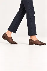 Mocasines planos de cuero marrón, con diseño de corte asimétrico en el empeine, punta fina y detalles con textura en la puntera y el talón.