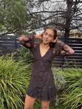 Vestido corto de encaje marrón, con escote en V, corte debajo del busto, mangas largas estilo trompeta y espalda transparente con volado en el ruedo.