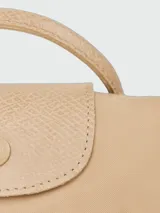 Cartera tipo pouch de la línea Le Pliage de Longchamp, color gris, con diseño minimalista, asa superior corta y cierre de solapa con botón a presión.