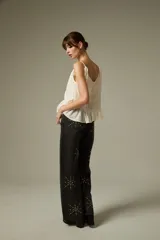 Musculosa negra de breteles finos, confeccionada en algodón con diseño plisado y detalles de encaje. Presenta un corte holgado con volados en el ruedo y escote profundo.