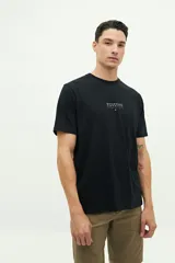 Remera de manga corta color beige con estampado gráfico en la espalda que representa el edificio Chrysler de Nueva York y texto descriptivo.