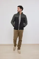 Campera capitoneada con capucha, con cambio de color tipo colorblock en verde militar y negro.