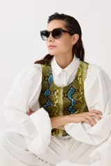 Top sin mangas confeccionado en cuero de oveja con estampado de piel de serpiente en tonos amarillo, azul y negro.