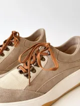 Championes de cuero color visón con cordones marrones, suela blanca y base color caramelo.