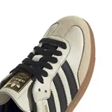 Championes Adidas modelo Samba OG, con diseño clásico de perfil bajo, parte superior de cuero en tono crema, icónicas tres tiras laterales en negro, refuerzo de gamuza en la puntera y suela de goma color caramelo.