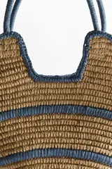 Bolso shopper de doble asa confeccionado en paja de papel trenzada, con diseño estructurado y líneas en tono azul en el cuerpo, asas y bordes.