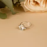 Anillo solitario de oro blanco 18k con una piedra central de aguamarina en corte ovalado y pequeños brillantes laterales engarzados en cuatro puntas.