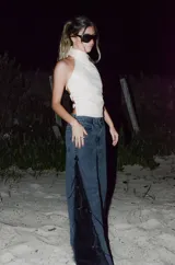 Jeans de corte wide leg en denim negro lavado, con inserción lateral de encaje negro adornado con flecos y lentejuelas.