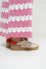 Zapatillas deportivas de cuero color beige con detalles en naranja y suela marrón.