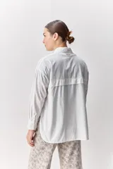 Camisa de algodón de calce relajado con cuello clásico, mangas largas con puños abotonados y cierre frontal con botones.